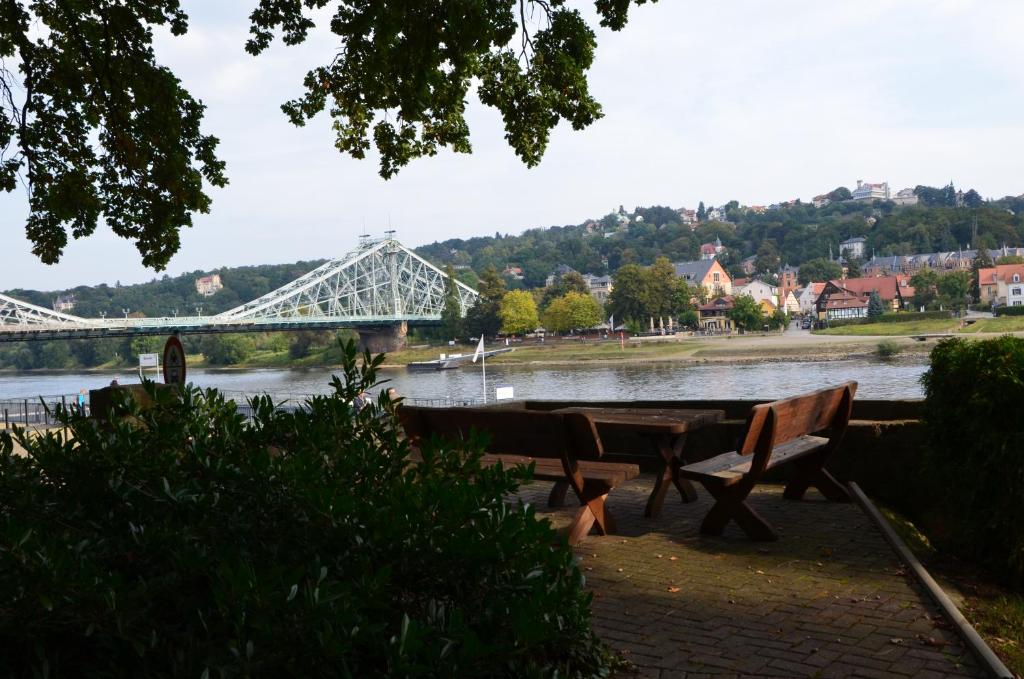 a river with benches and a bridge in the background at Ferienwohnung an der Elbe in Dresden