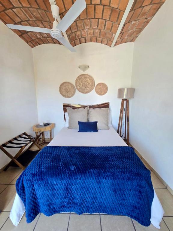 a bedroom with a bed with a blue blanket on it at Tayau Bungalows B6 in Lo de Marcos