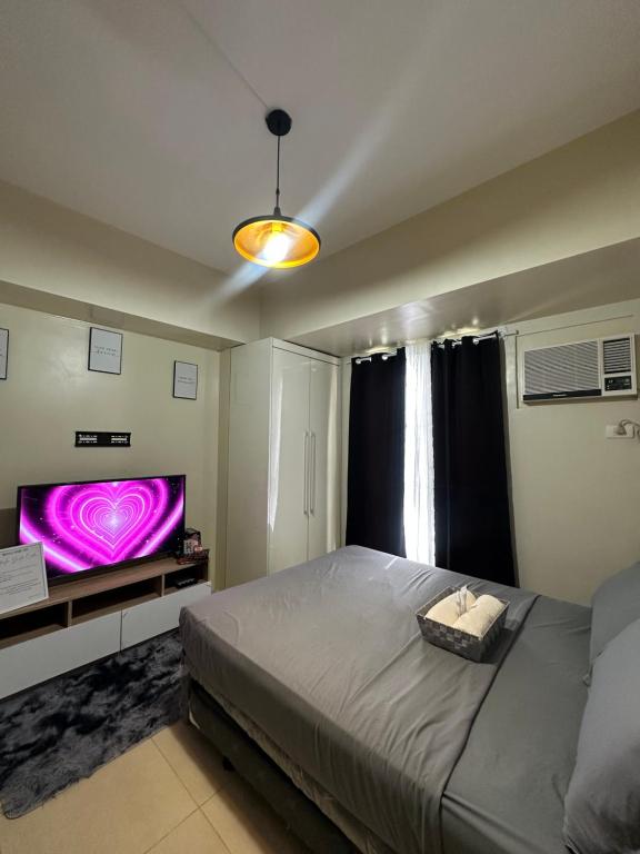 a bedroom with a large bed and a flat screen tv at Riala Suite Cebu in Sampong
