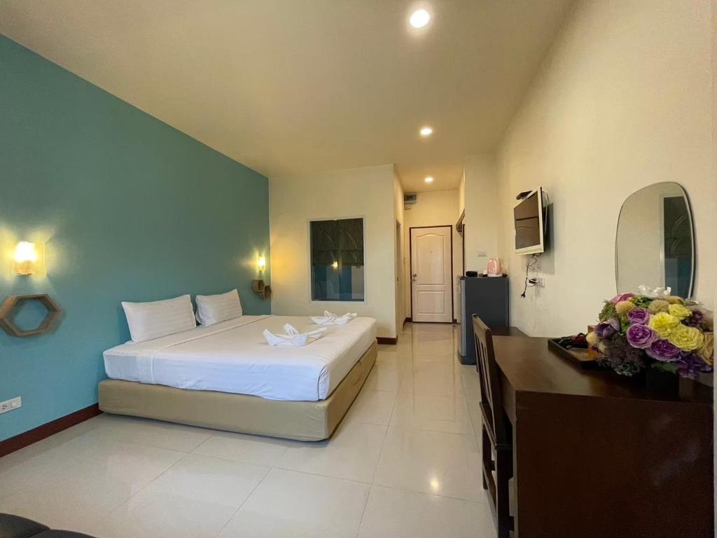 a bedroom with a large white bed and blue walls at โรงแรมพันวลี in Ban Hua Phrong