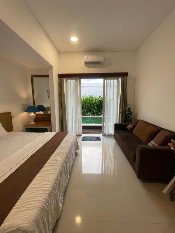 a bedroom with a bed and a couch and a window at Ariani Villa in Jimbaran
