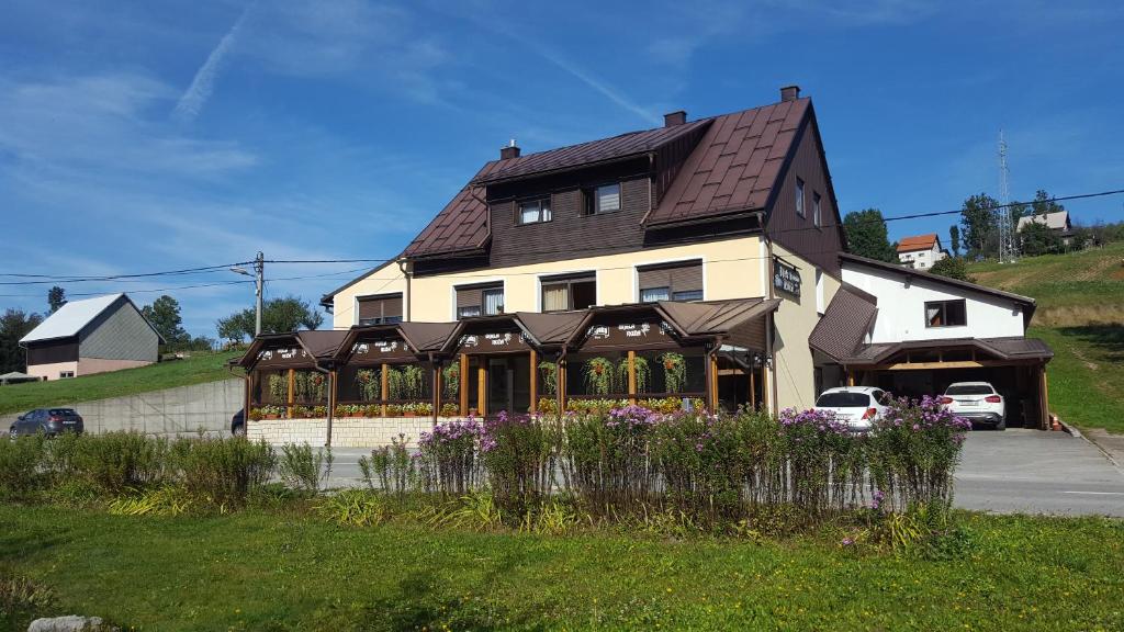 a house on a hill with flowers in front of it at Pansion i restoran Bijela Ruža in Ravna Gora