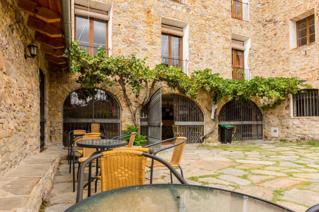un patio con mesas y sillas frente a un edificio en Alberg La Solana, en Salàs de Pallars
