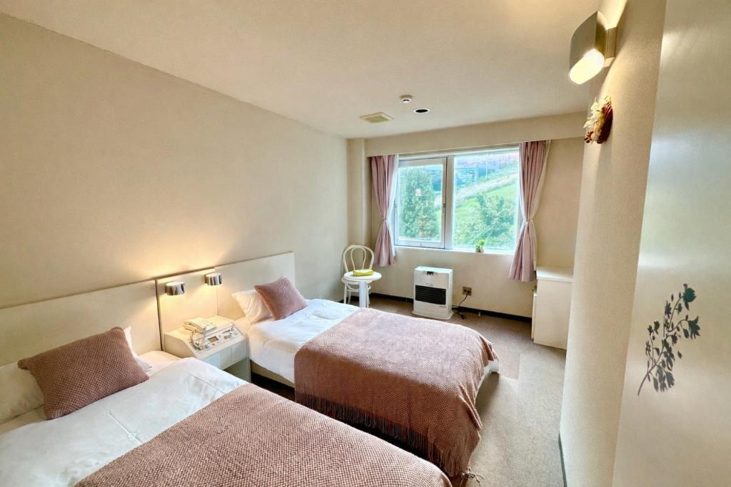 a hotel room with two beds and a window at 雪场缆车站旁 Hotel Justice-Ski IN Ski OUT-独立卫浴 in Seki