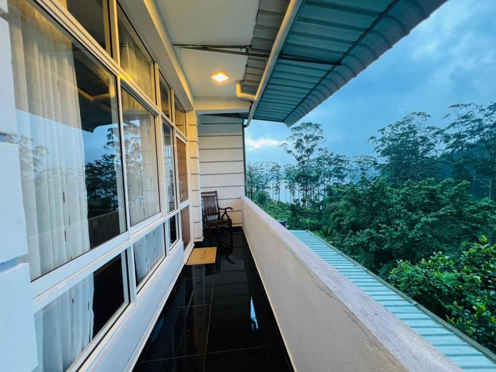 a balcony of a house with a view of trees at Adams Peak Lake Resort in Nallathanniya