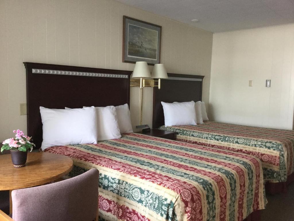 two beds in a hotel room with a table and chairs at Inn Town Motel in Waupun