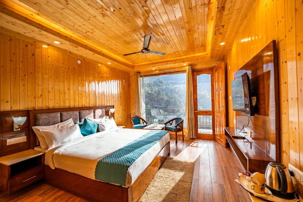 a bedroom with a bed and a large window at Vedikant Pine Tree Resort in Chail