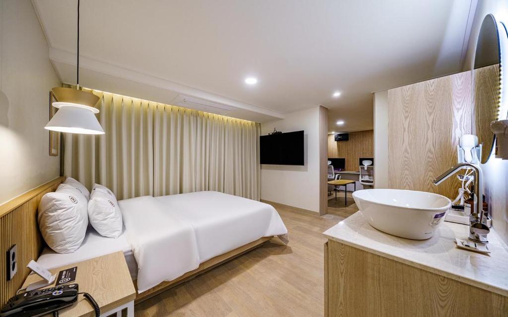 a hotel room with a bed and a sink at Daejeon Brown Dot Wolpyeong in Daejeon