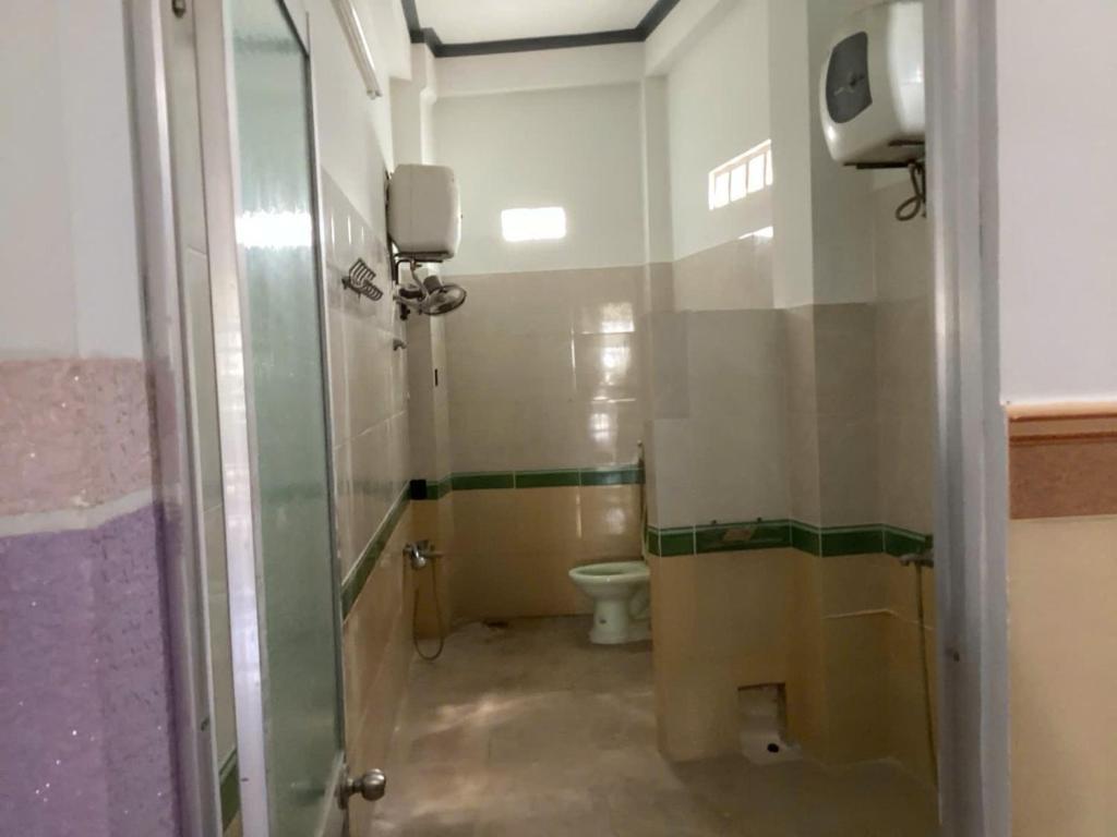 a bathroom with a toilet and a glass door at TuNo Homestay in Tuy Hoa