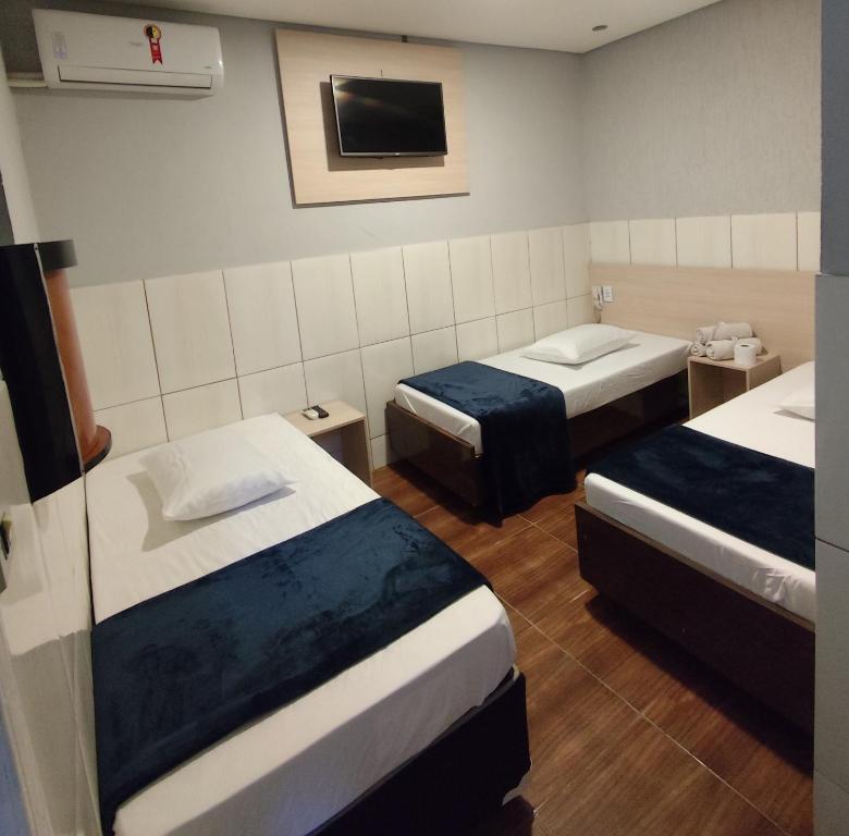 a hotel room with two beds and a tv at Hotel Anoitecer - 100 metros metrô Carandiru, 700 metros Rodoviária do Tietê, 900 metros Aeroporto Campo de Marte, 1,4 km Expor center norte, 1,8 km Distrito do anhembi! Oferecemos como cortesia café da manhã e estacionamento! in São Paulo