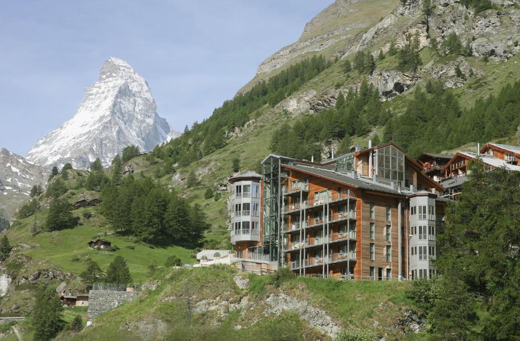 um hotel nas montanhas com uma montanha ao fundo em The Omnia em Zermatt