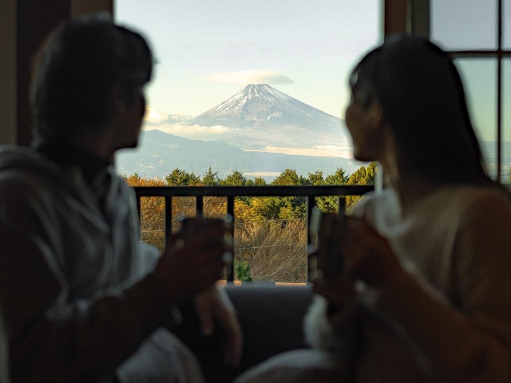 a couple sitting on a couch looking at a mountain at 貸ログハウス奏 in Izunokuni