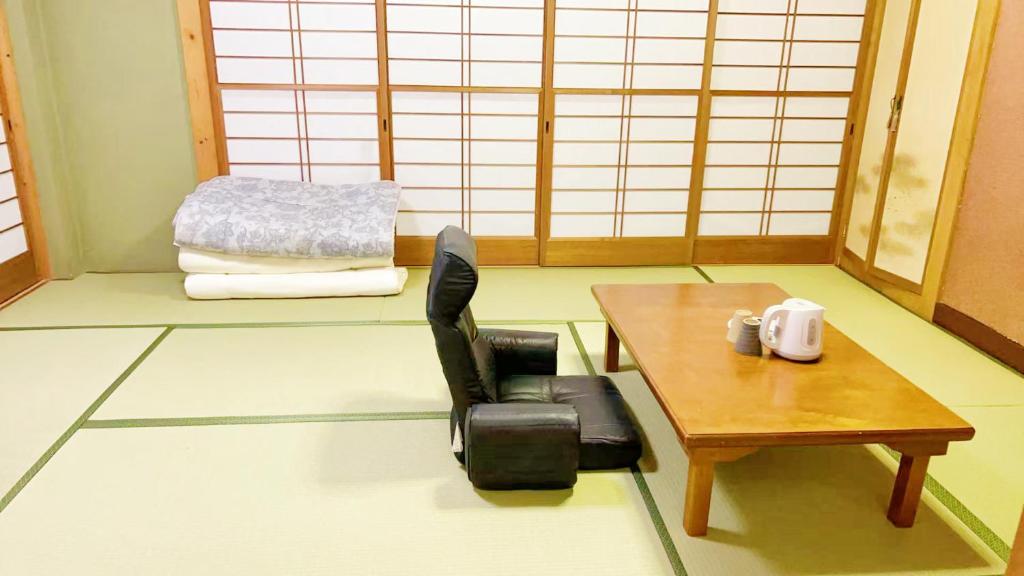 a room with a chair and a table and a bed at 富士見旅館101 in Fujiyoshida
