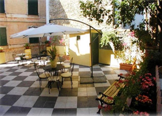 a patio with a table and chairs and an umbrella at Camere D'Autore La Poesia in Monterosso al Mare