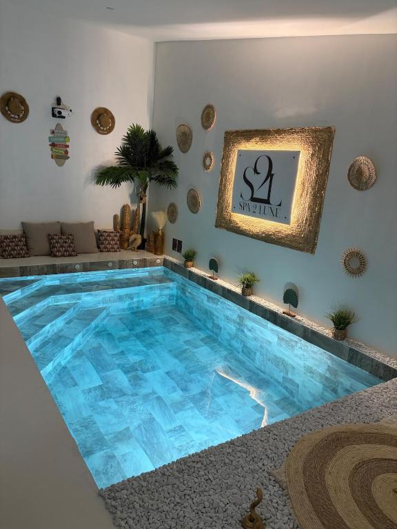 ein großer blauer Pool mit einer Uhr an der Wand in der Unterkunft Spa2Luxe - Oasis Cachée in Saint-Quentin