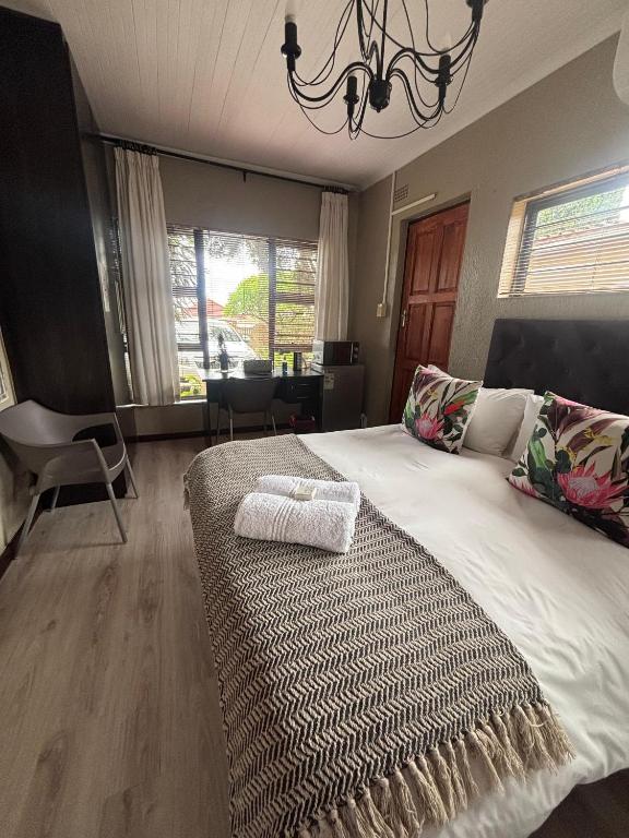 a bedroom with a large bed with a chandelier at Amru Guesthouse B&B in Brackenfell