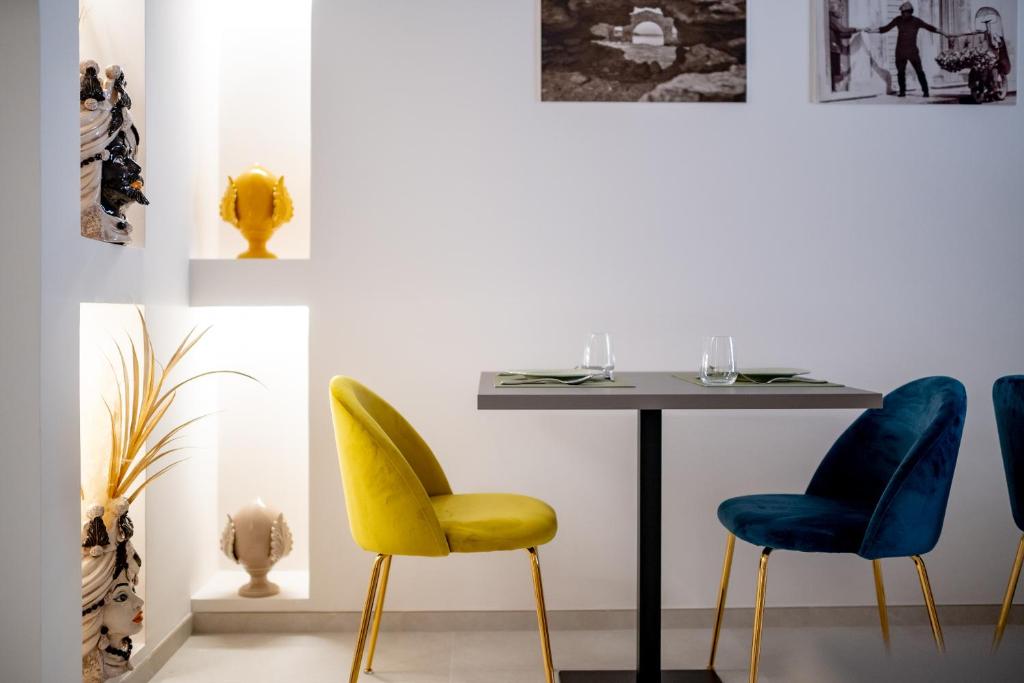 a dining room with a table and yellow and blue chairs at Luxury B&B Maison Madre in the historic center of Avola in Avola