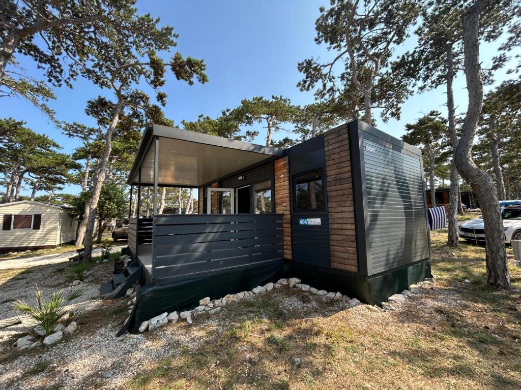 a small black house on a hill with trees at Forest House Razanac in Ražanac