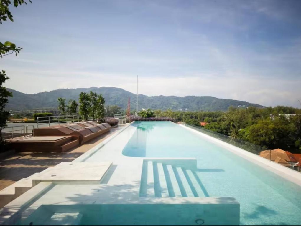 a large swimming pool with chairs and mountains in the background at Laguna SkyPark in Laguna Phuket