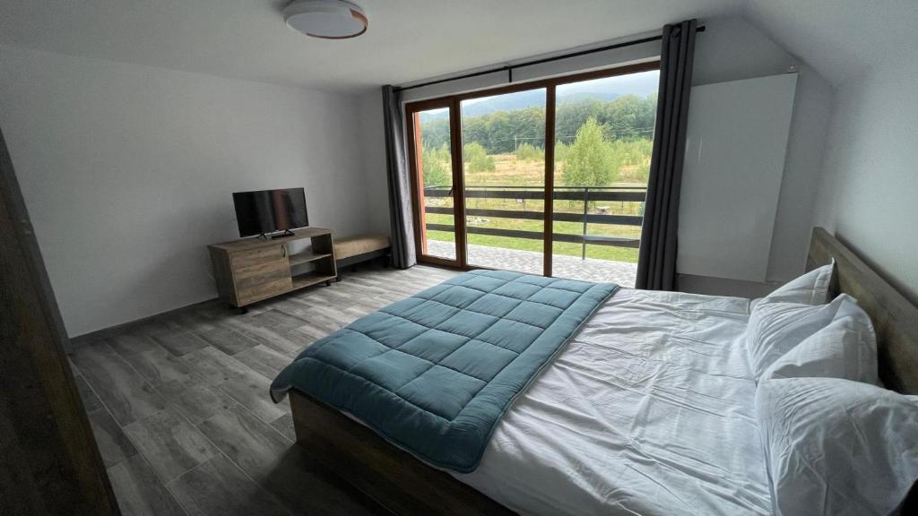a bedroom with a bed and a large window at Pensiunea Panoramic in Stațiunea Climaterică Sâmbăta
