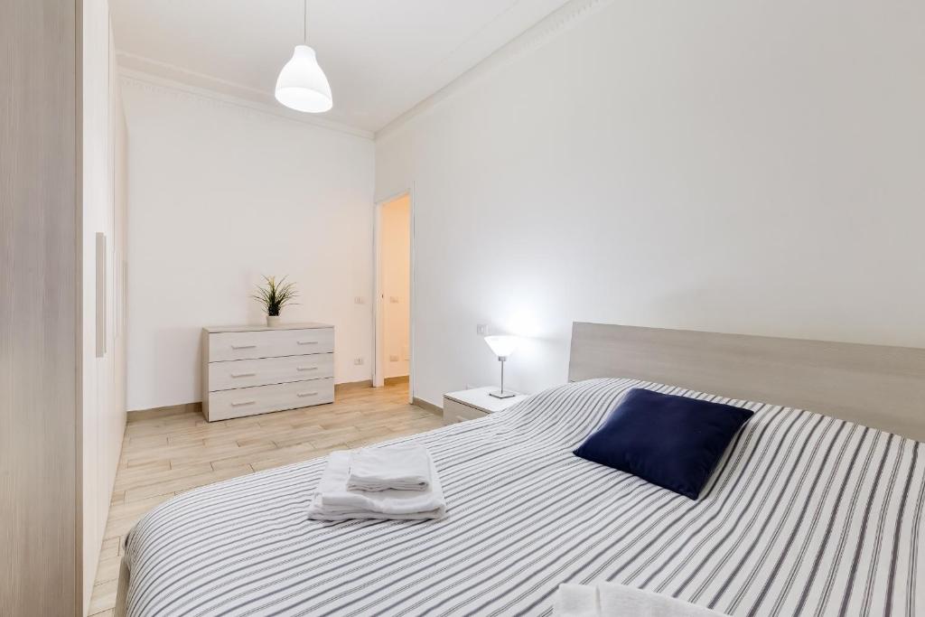 ローマにあるAppartamento Cenedaの白いベッドルーム(大型ベッド1台、青い枕付)