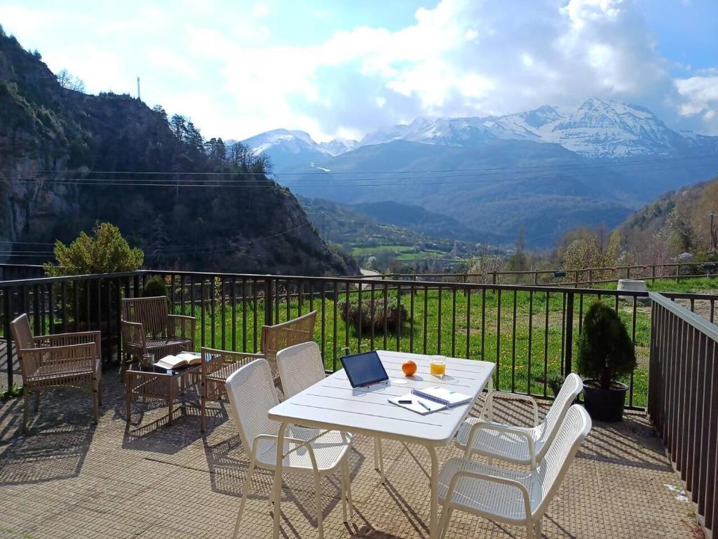 a white table and chairs on a balcony with mountains at La Terraza de Escarrilla, con piscina in Escarrilla