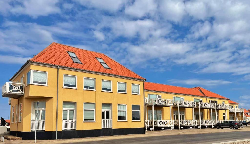 a yellow building with an orange roof on a street at Plesners Havnelejligheder in Skagen