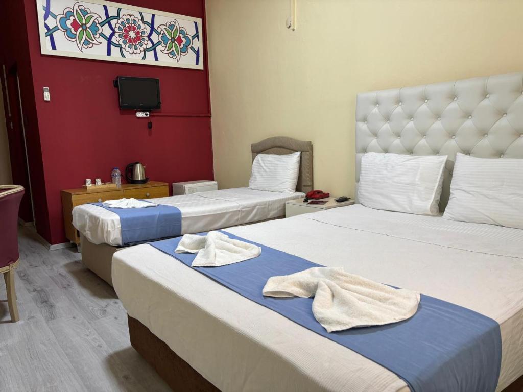 two beds in a hotel room with towels on them at Elflora Otel in Ceyhan