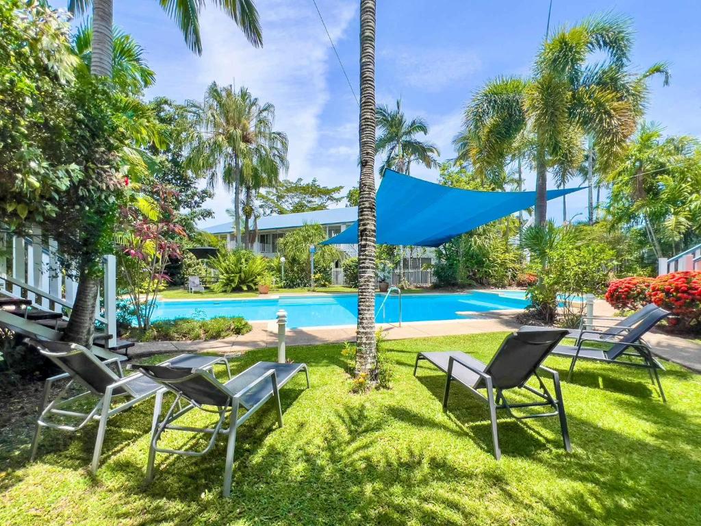 a yard with chairs and a swimming pool at Coral Mango in Airlie Beach