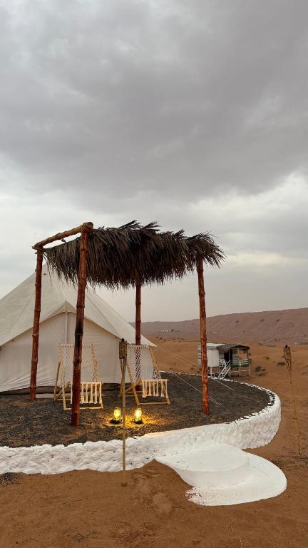 a tent in the middle of the desert with a fire at Royal desert camp in Al Raka