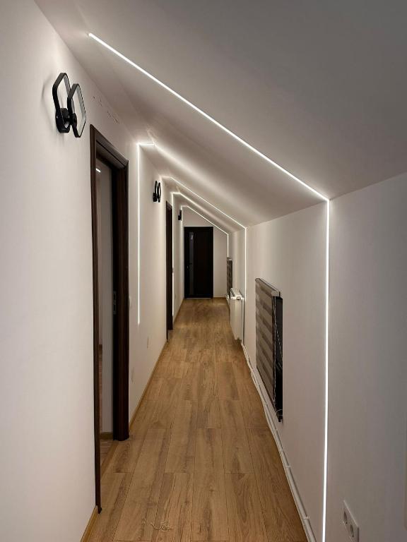 a hallway with a white wall with a light on it at The Forest Nest Apartment in Sărmaş