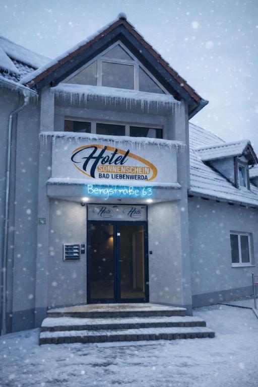 a building with a sign on it in the snow at Hotel Sonnenschein in Bad Liebenwerda