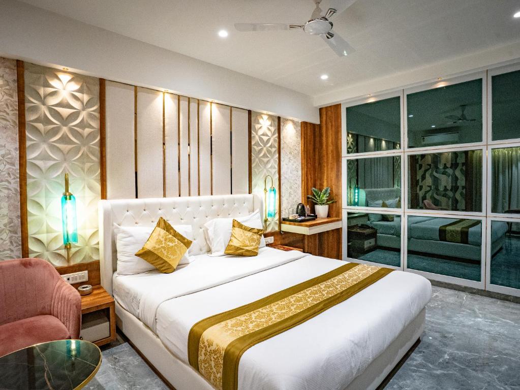a bedroom with a large white bed and a chair at Hotel Spencer-Navi Mumbai in Navi Mumbai