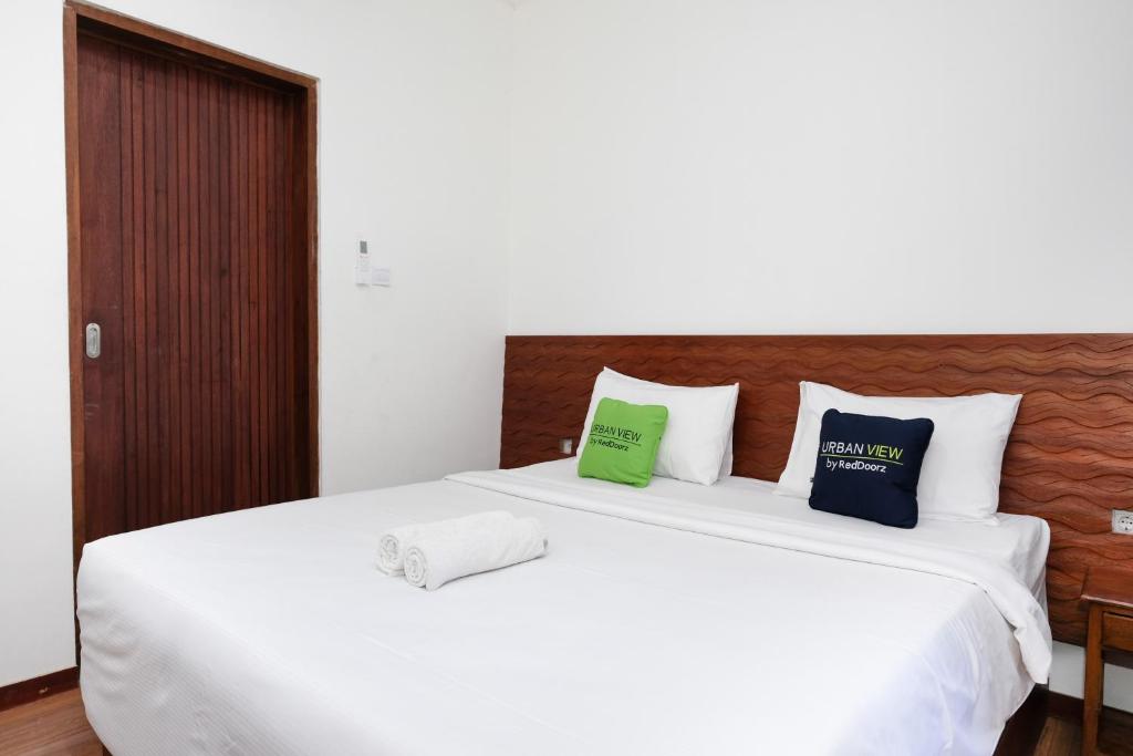 a bedroom with a white bed with two pillows on it at Urbanview Hotel Arta Guna Casa in Kerobokan