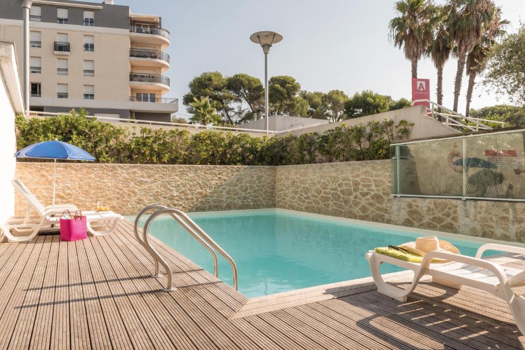 a swimming pool with two lounge chairs next to a building at Appart'City Classic Antibes in Antibes