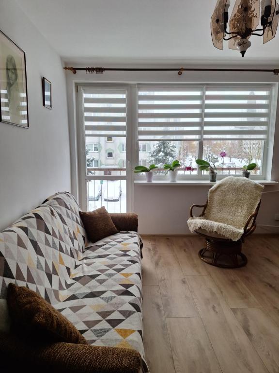 a living room with a couch and a chair and windows at Apartament Cichy Zakątek in Ruciane-Nida