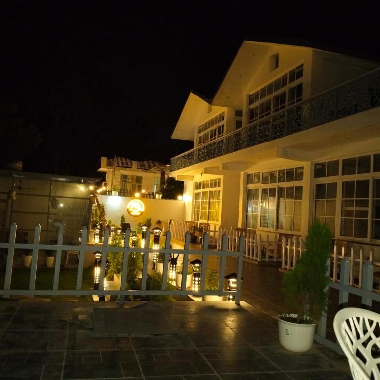 a building at night with a white fence and chairs at leisure valley resort in Jhājra
