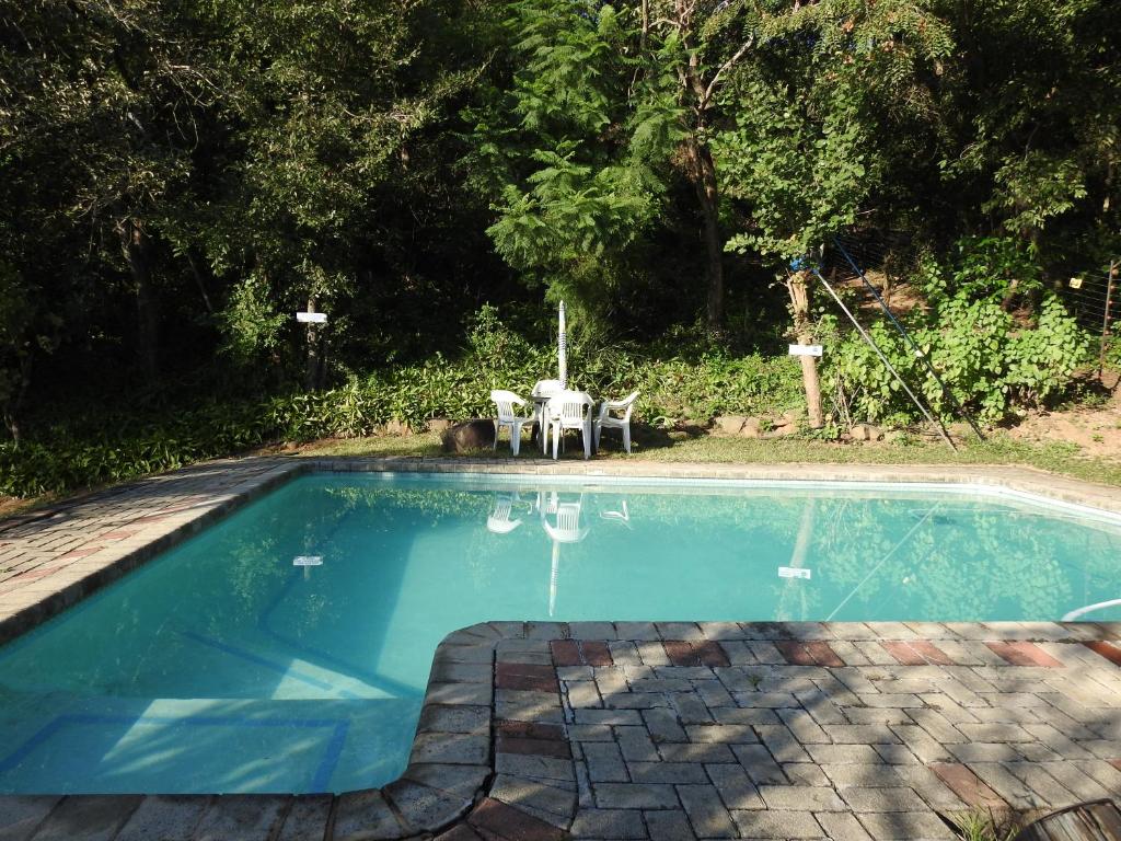 a swimming pool with a table and chairs next to it at Impala Niezel Lodge & Guest House in Hazyview