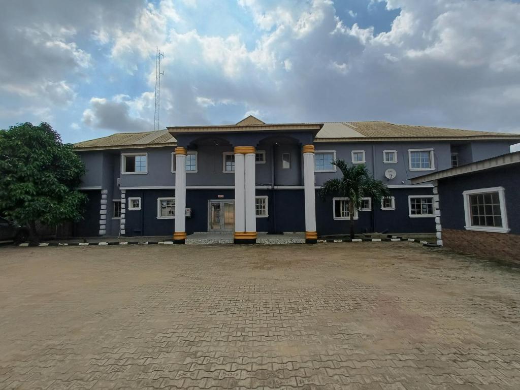 a blue building with white columns in a courtyard at AP Luxury Inn in Idowu