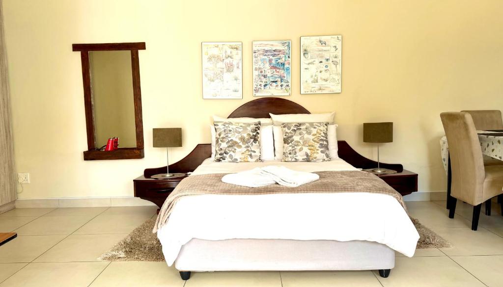 Un dormitorio con una gran cama blanca con espejo. en Lyn's Self Catering, en Swakopmund