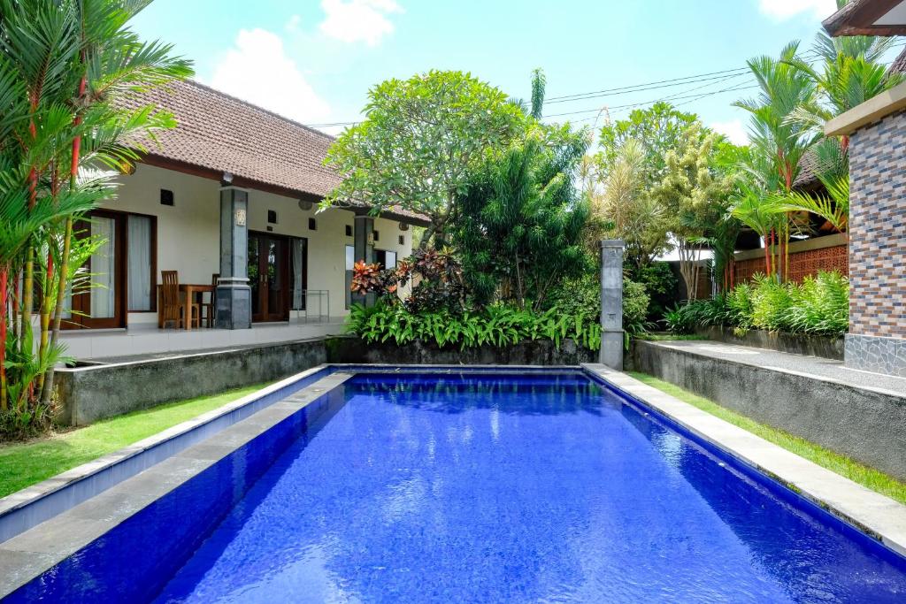 a swimming pool in front of a house at Lilis Cempaka Mas Guesthouse in Canggu