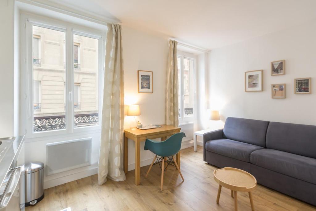uma sala de estar com um sofá e uma mesa em Les Toits de Paris em Paris