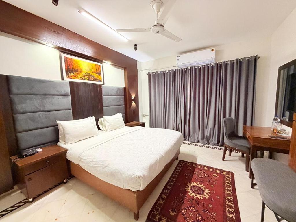 a hotel room with a bed and a desk and a table at Comfort Lodge Executive in Islamabad