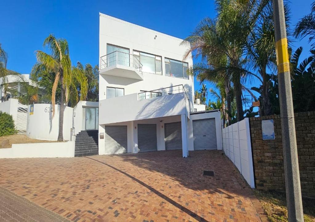 a white house with palm trees in front of it at The White House at Plattekloof in Plattekloof