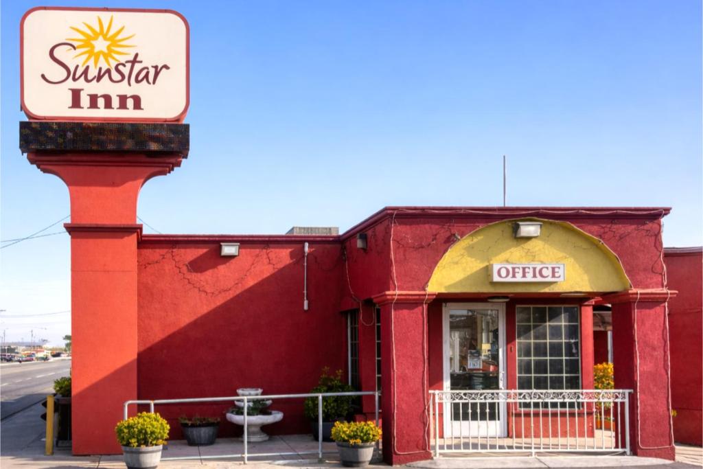 a red building with a sign on the side of it at Sun Star Inn Los Banos in Los Banos
