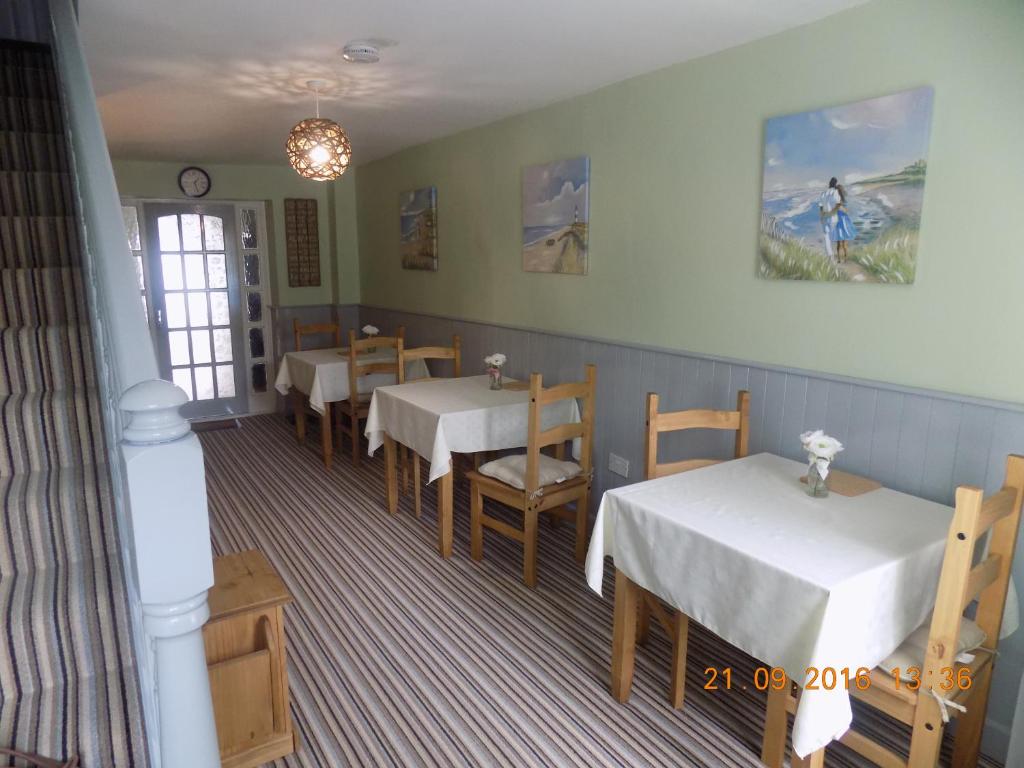 a dining room with tables and chairs and a window at Cú Chulainns Accommodation in Westport