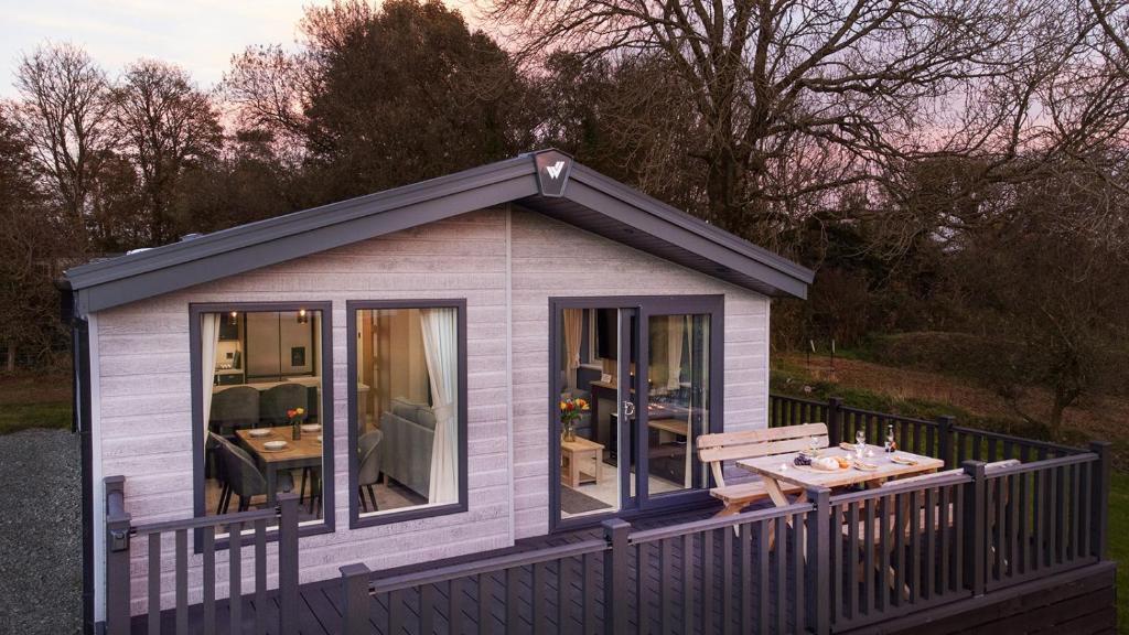 a small shed with a table on a deck at Olive Lodge Benllech in Brynteg