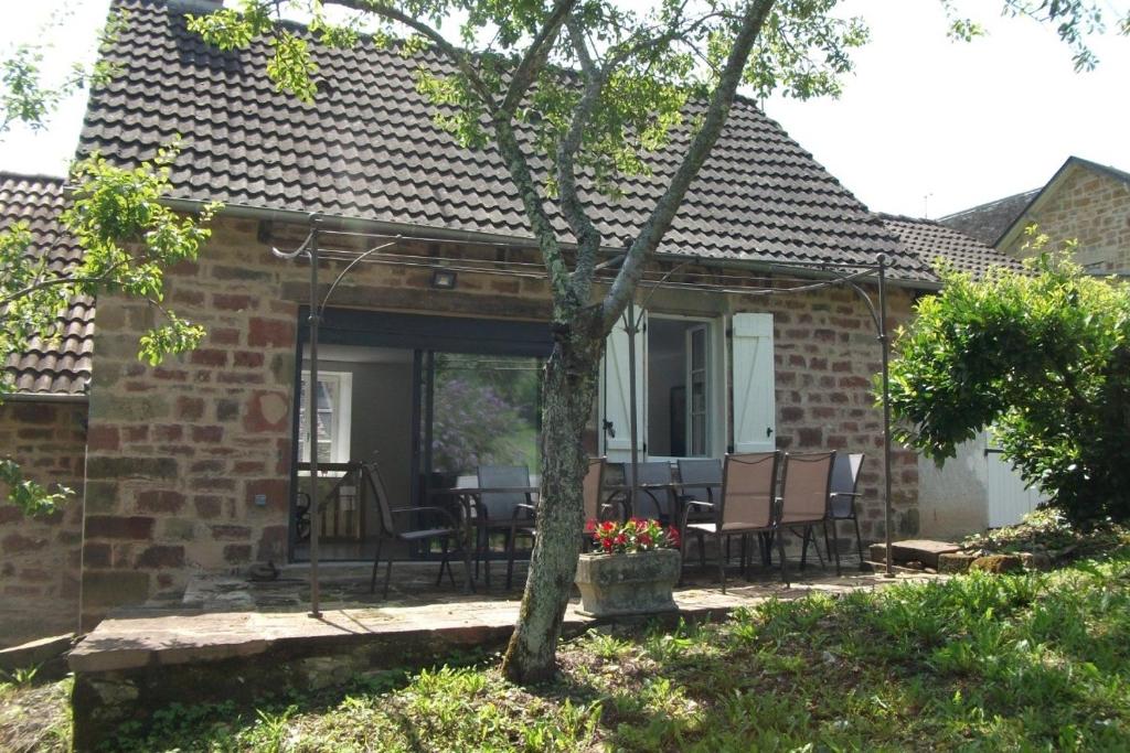 a brick house with a patio with a table and chairs at Gîte Les Noyers in Noailhac