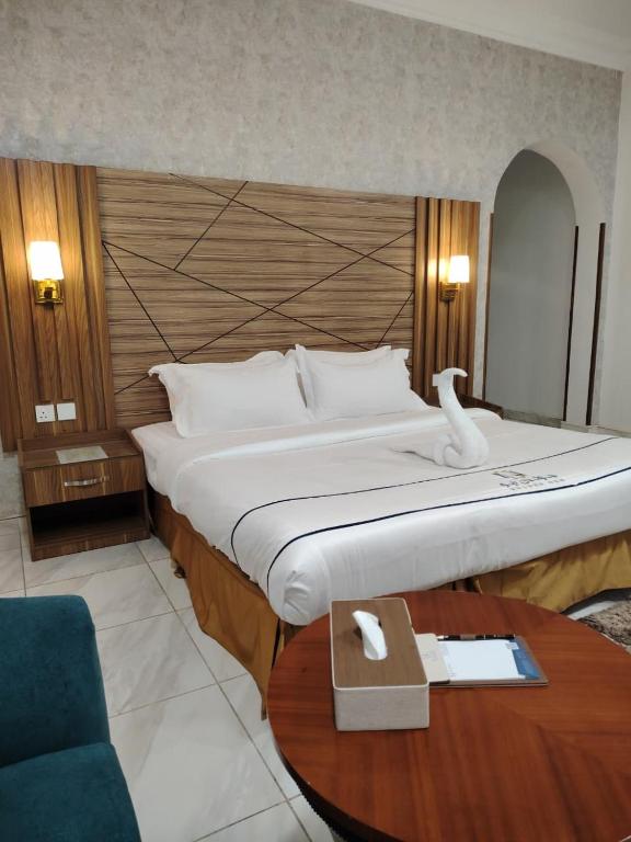 a hotel room with a large bed and a table at رندة المدن للشقق المخدومة in Jazan