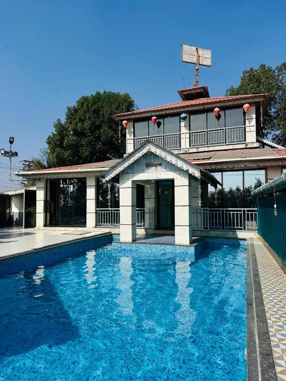 a house with a swimming pool in front of a building at Celebrations Party House in Kolhapur
